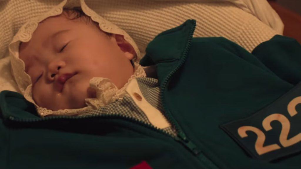 bebe com uma roupa verde com numero grafado nela
