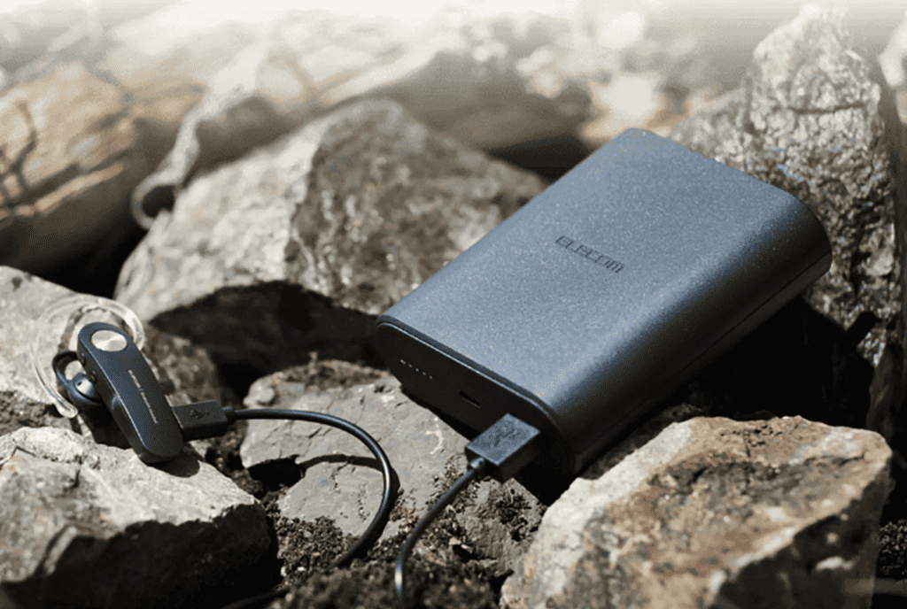 imagem mostra um carregador portátil em cima de pedras sob o sol