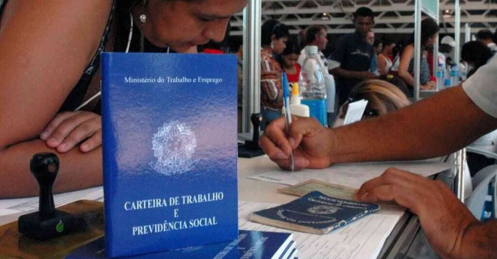 Profissional em posto de atendimento ao trabalho e carteira de trabalho em primeiro plano