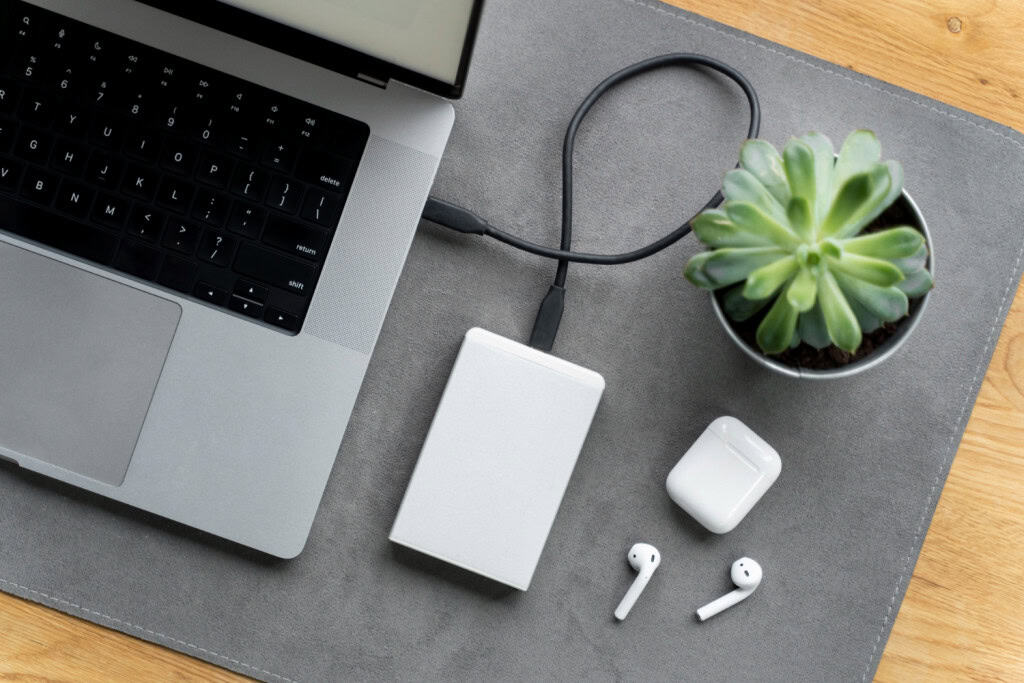 notebook sendo carregado em um power bank com fones de ouvido do lado