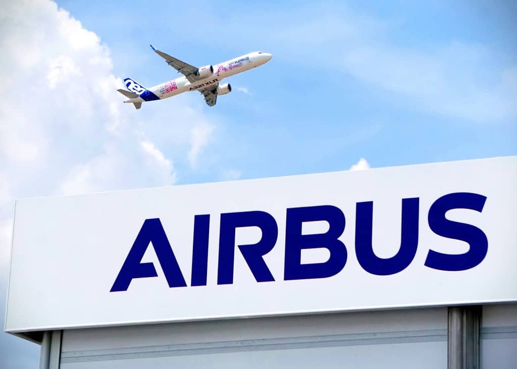 Logo da Airbus na fachada de um prédio com um avião voando acima da edificação