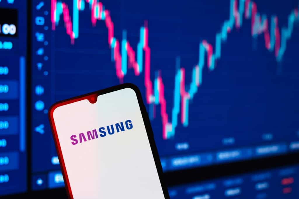 Ao fundo, gráfico financeiro; à frente, logo da Samsung em smartphone