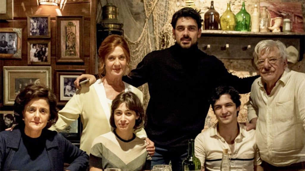 imagem mostra os principais personagens do filme duetto, reunidos numa mesa de jantar
