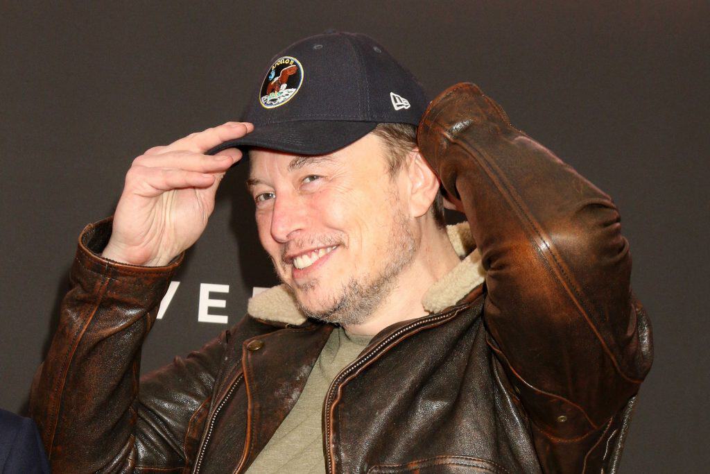 Elon Musk colocando um boné e sorrindo