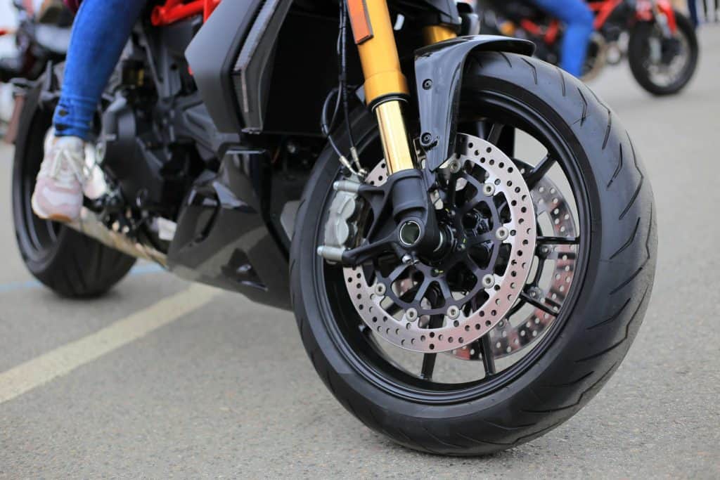 imagem mostra o close up do pneu de uma moto, cujo pneu tem freio a disco