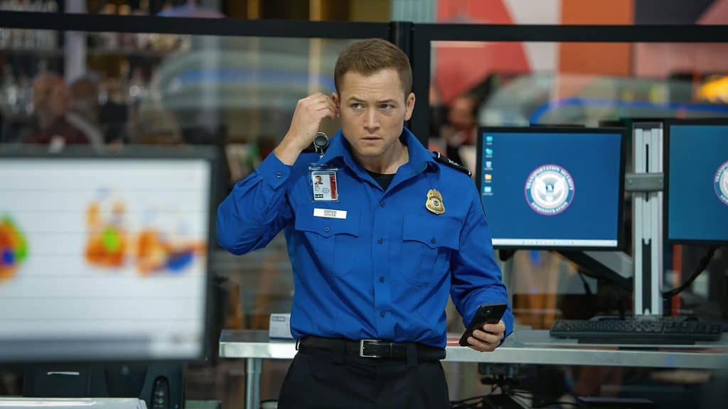 imagem mostra um agente de segurança de um aeroporto colocando um ponto eletrônico no ouvido