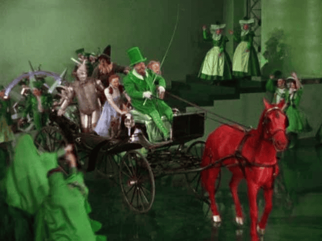 cena de O mágico de oz com um cavalo vermelho e os outros personagens com roupa verde