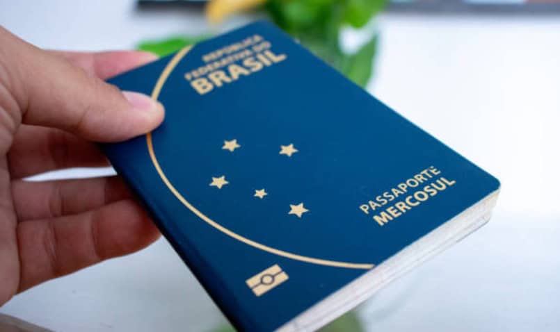 pessoa segurando modelo anterior do passaporte brasileiro